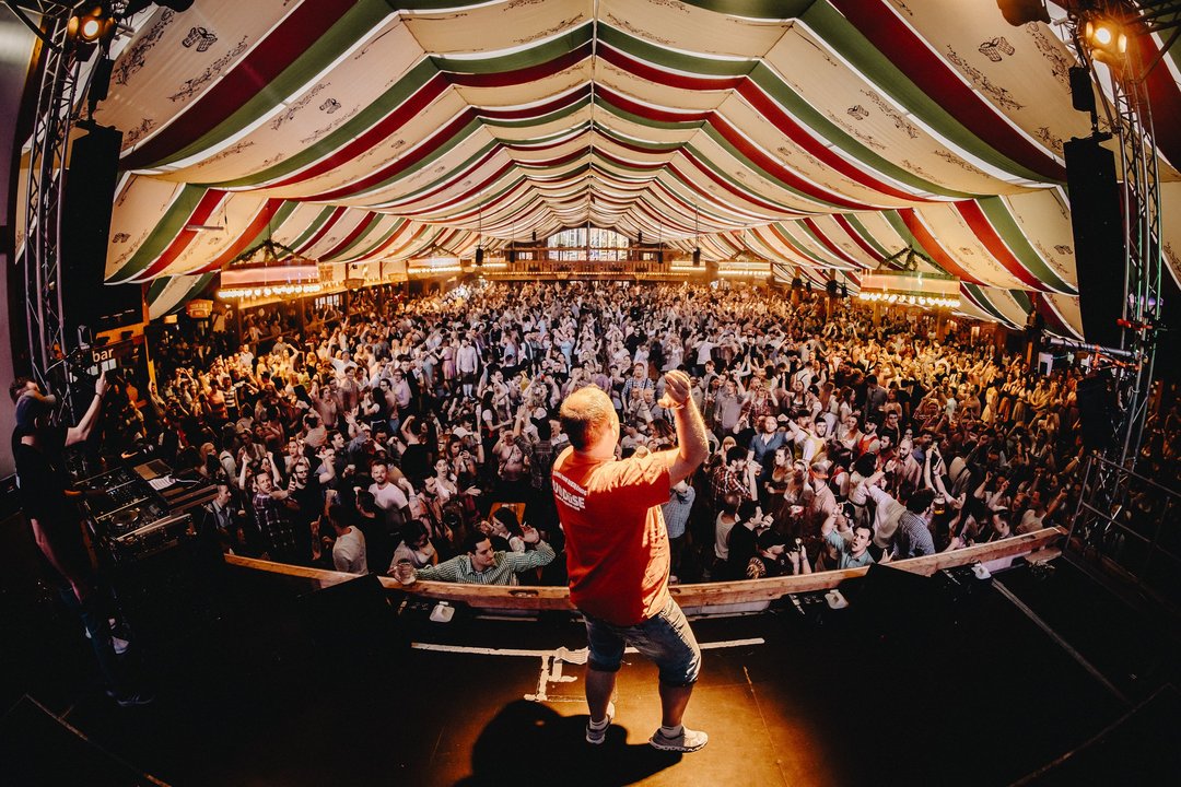 Ein Musiker macht auf einer Bühne vor dem Publikum im Wasenwirt-Zelt Stimmung