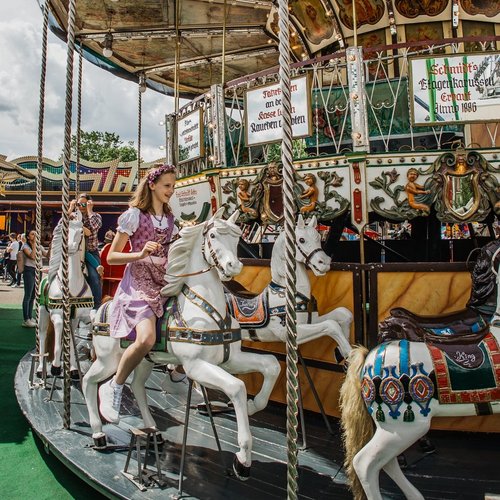 Ein Mädchen sitzt auf einem Pferd in einem Karussell