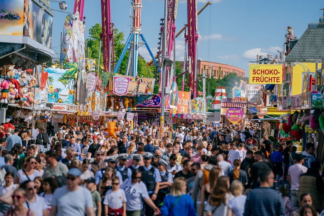 Unzählige Menschen laufen über den Festplatz, vorbei an zahlreichen Ständen und Buden mit ihren Angeboten.