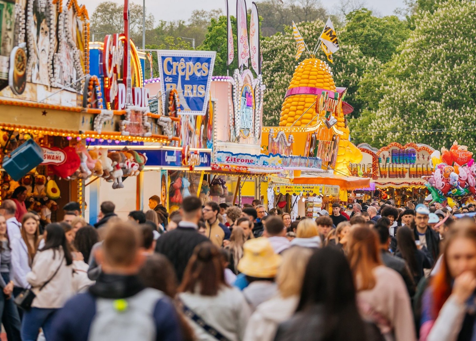 Festgasse mit vielen Buden und Menschen.