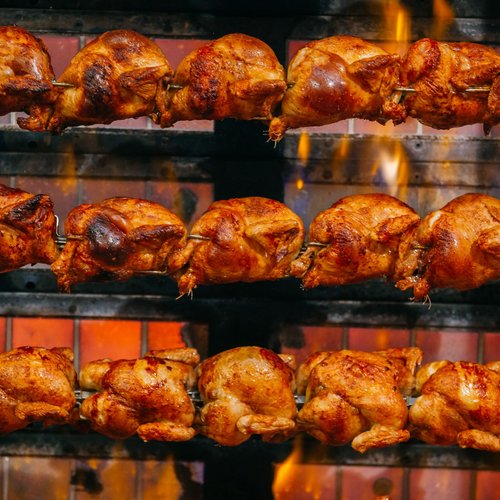 Mehrere saftig gegrillte Hähnchen auf Drehspießen.