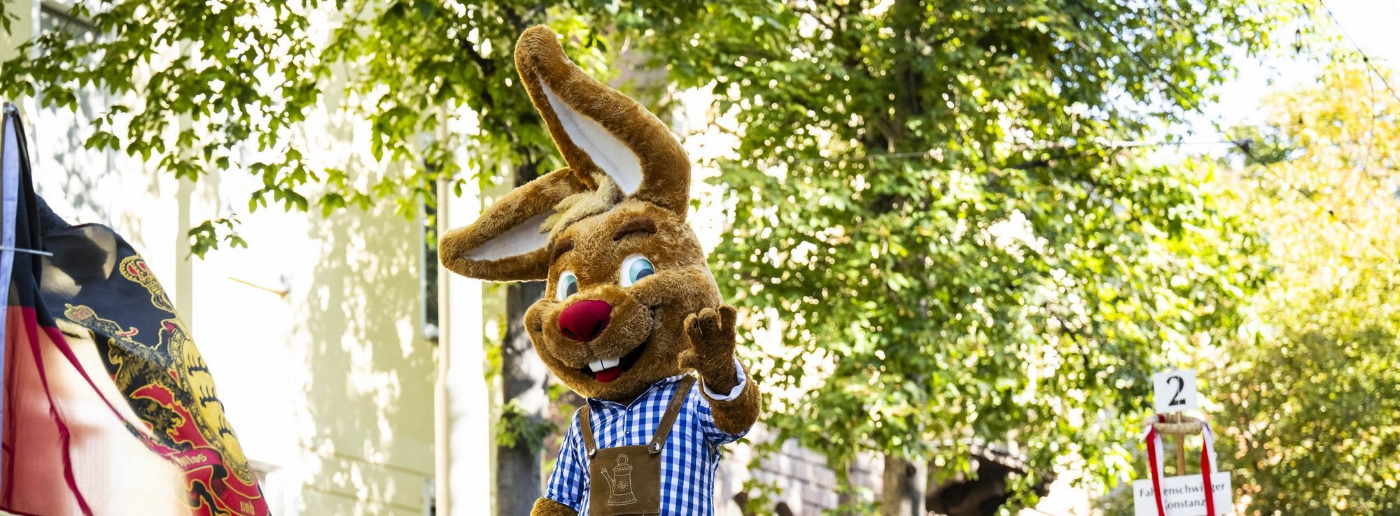 Das Maskottchen "Wasi" läuft beim Volksfest-Umzug durch Bad Cannstatt und winkt.