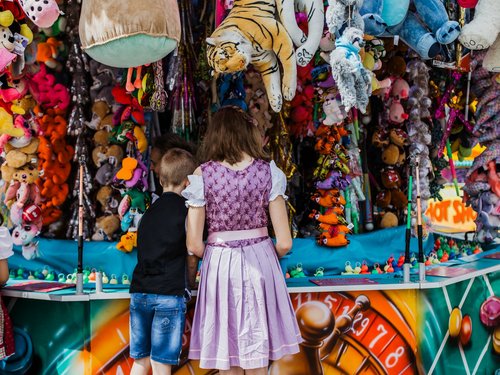 Ein Mädchen und ein Junge stehen an einem Stand mit Entenangeln und versuchen ihr Glück.
