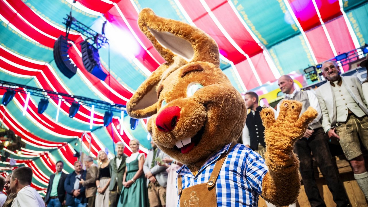 Maskottchen Wasi im Festzelt bei der Eröffnung, winkt fröhlich in die Kamera.