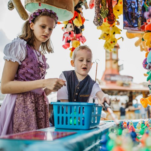 Ein Junge und ein Mädchen in Trachten versuchen ihr Glück beim Entenangeln
