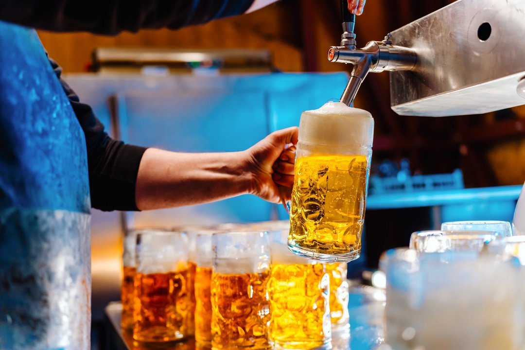 Jemand zapft an einem Hahn ein frisches Bier in einen Maßkrug